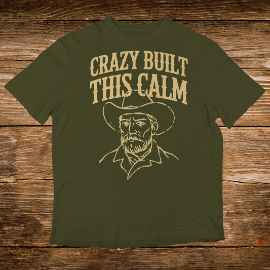 Olive t-shirt with "Crazy Built This Calm" text and cowboy illustration.