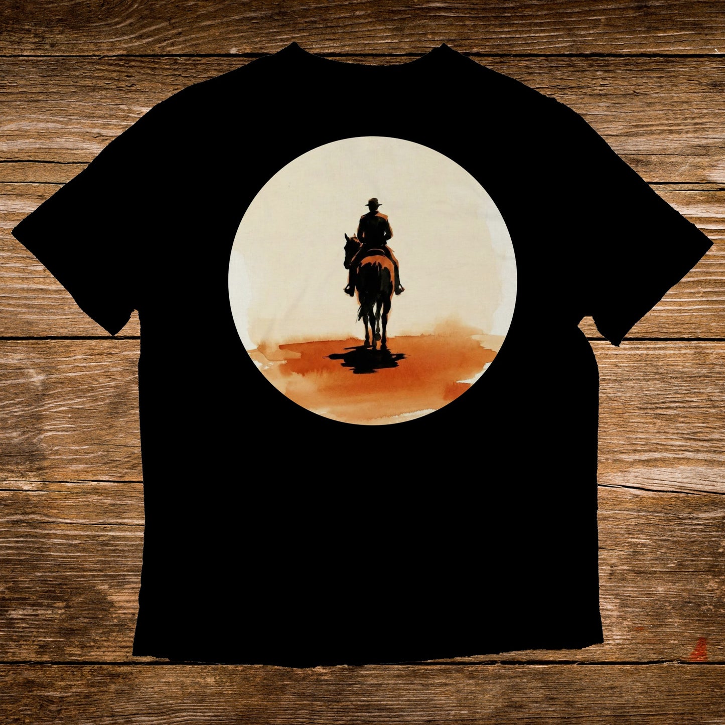 Black t-shirt with artwork of a cowboy on horseback against a sunlit background.