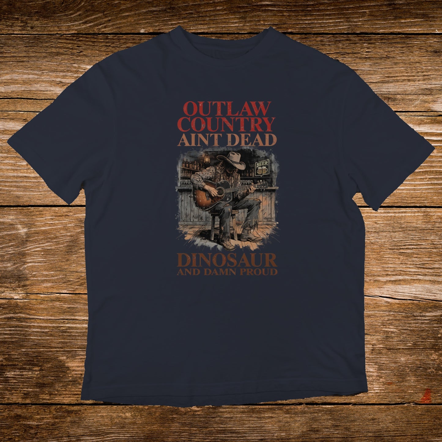 Outlaw Country Ain't Dead Dinosaur and Damn Proud t-shirt with cowboy playing guitar.