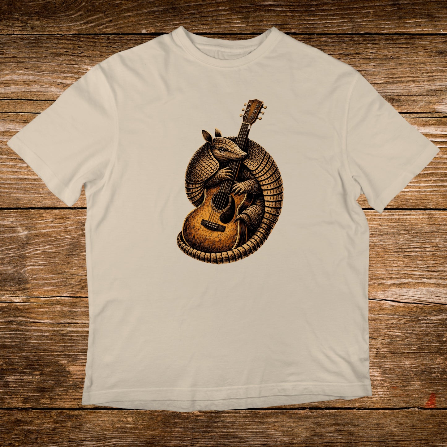 Illustration of an armadillo playing an acoustic guitar on a cream t-shirt.