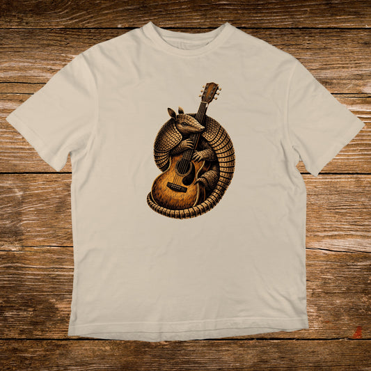 Illustration of an armadillo playing an acoustic guitar on a cream t-shirt.
