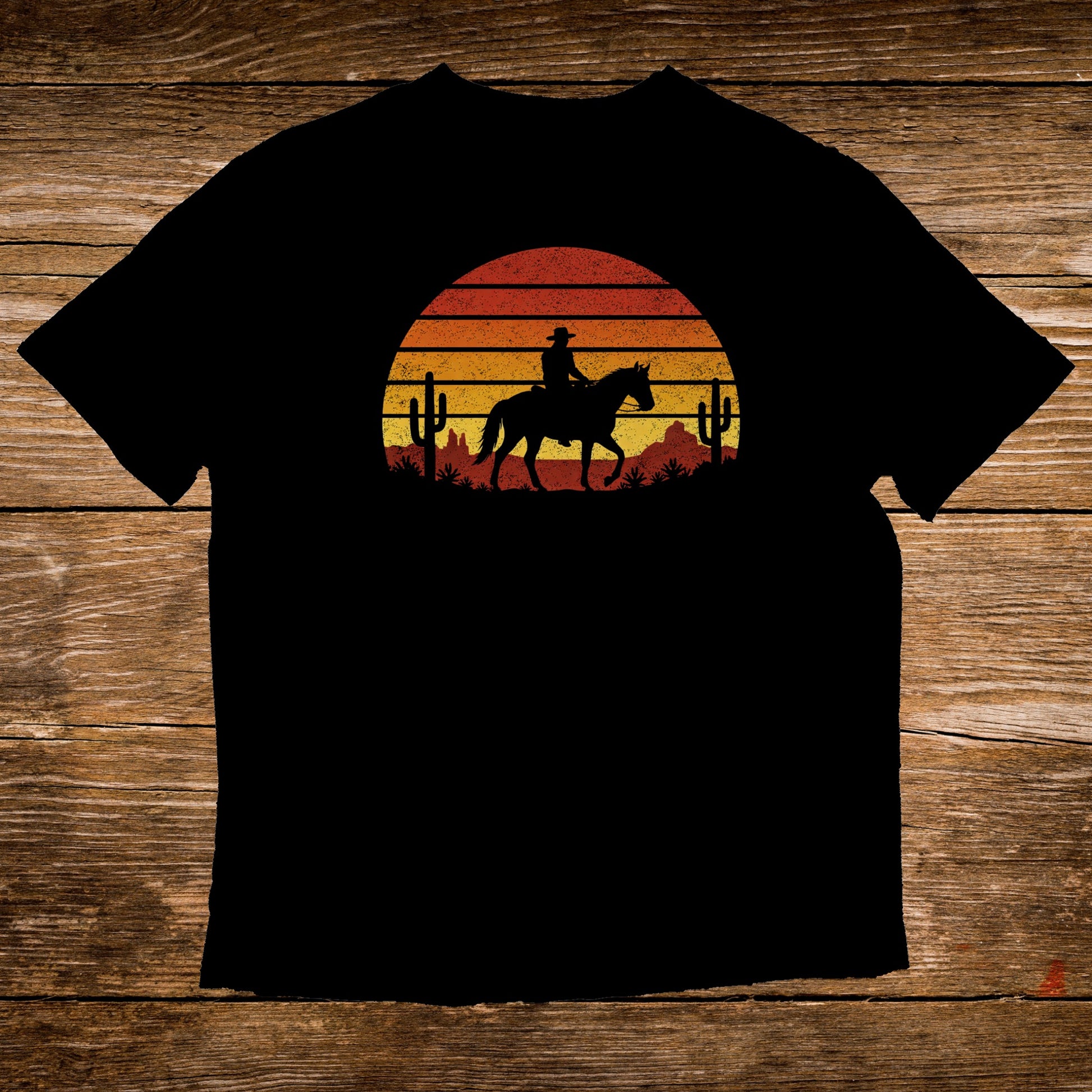 Silhouette of cowboy on horseback against a sunset and cacti.