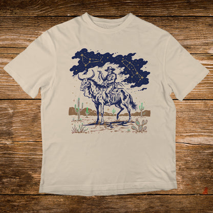 Cowboy on horseback under starry sky with desert landscape.