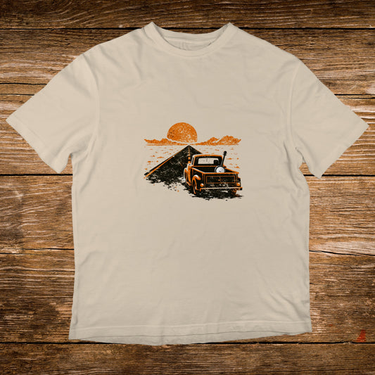 Orange truck driving on a dirt road towards a sunset.
