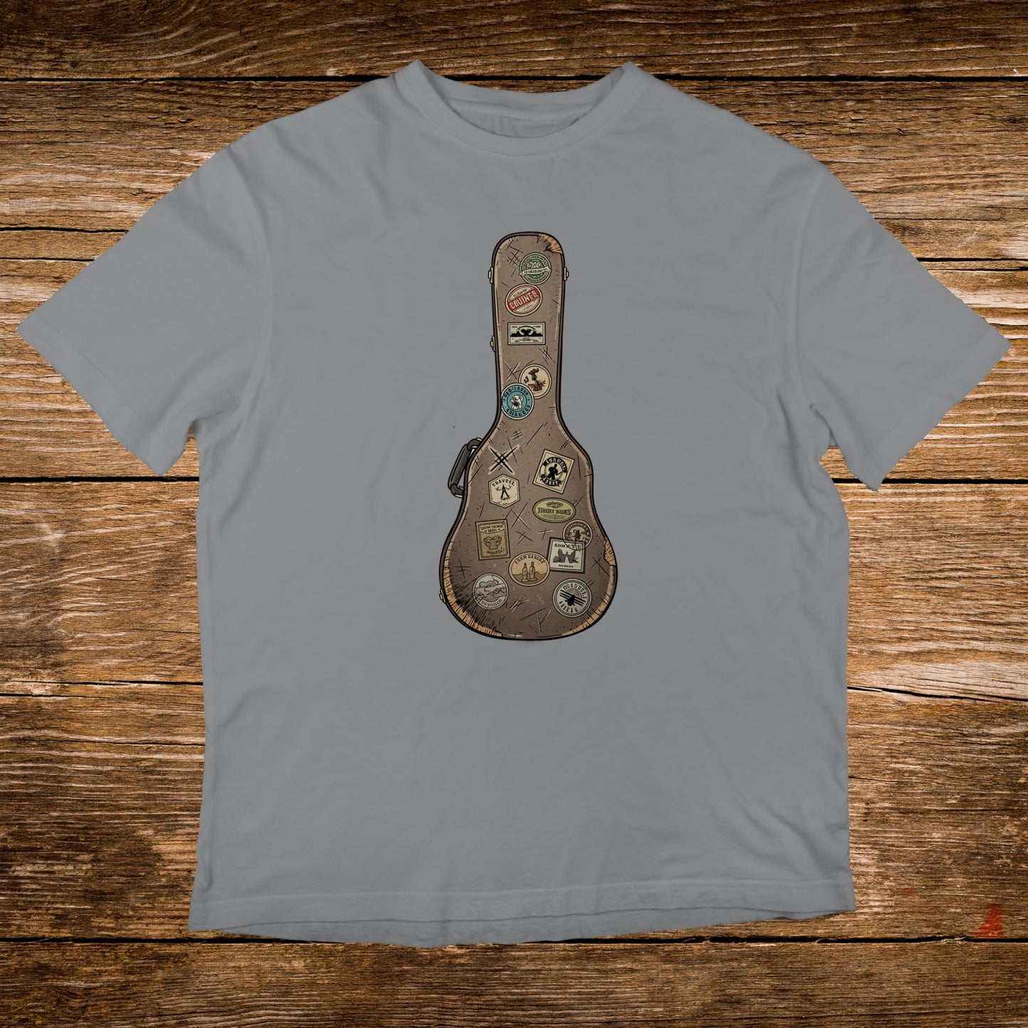 Guitar case covered in travel stickers on a grey t-shirt.