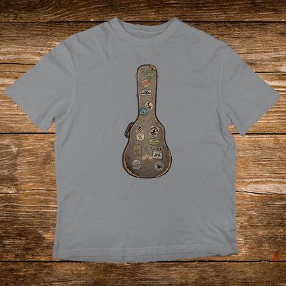 Guitar case covered in travel stickers on a grey t-shirt.