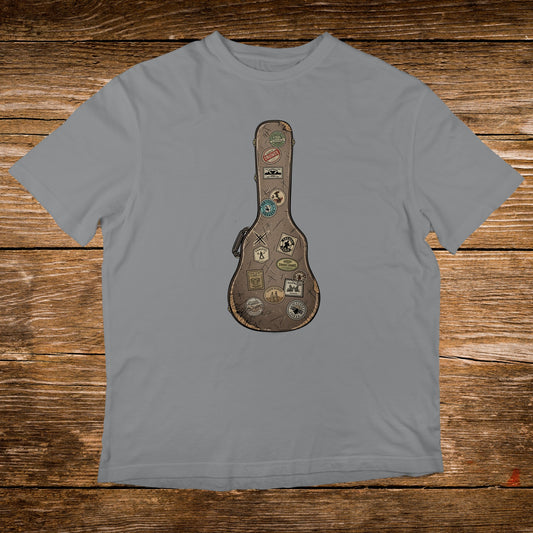 Guitar case covered in travel stickers on a grey t-shirt.