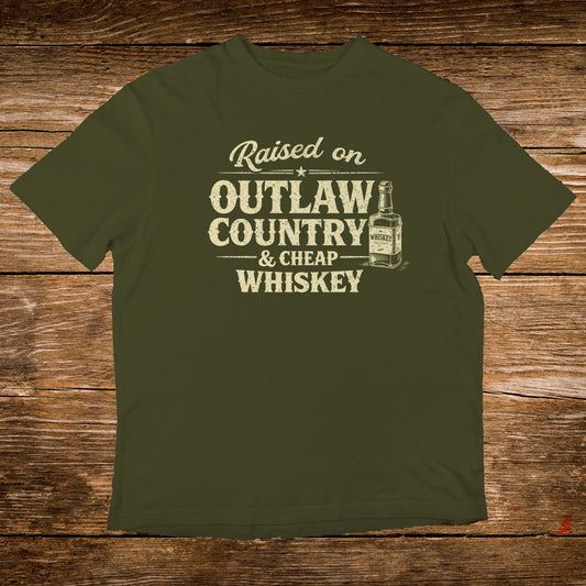 Olive green t-shirt with "Raised on Outlaw Country & Cheap Whiskey" text and whiskey bottle graphic.