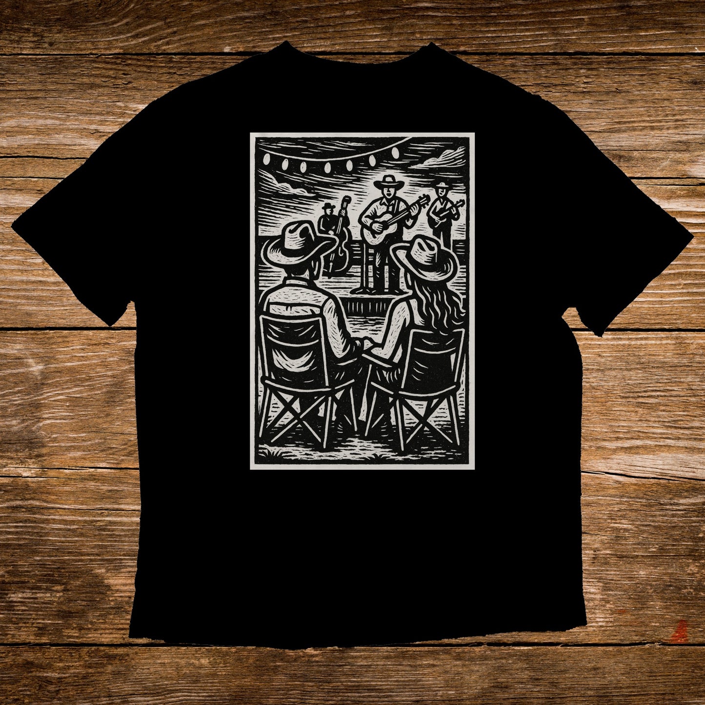 Black t-shirt with woodcut style illustration of a couple watching an outdoor band.