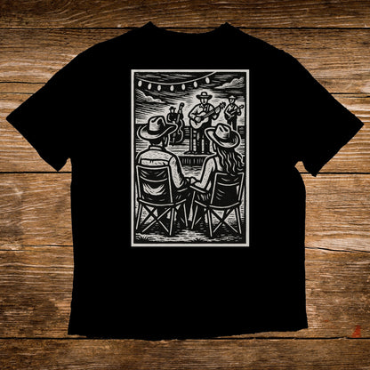 Black t-shirt with woodcut style illustration of a couple watching an outdoor band.