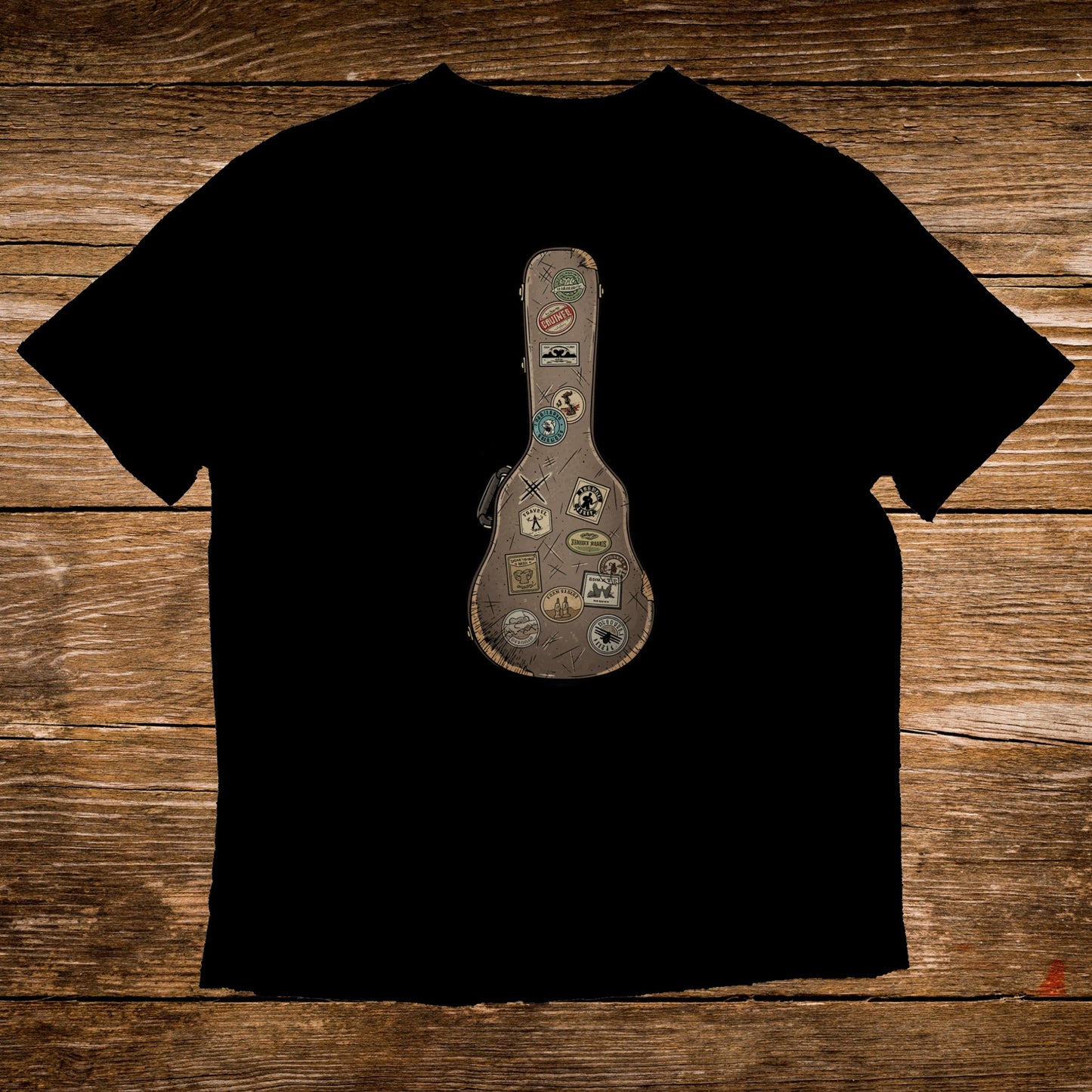 Black t-shirt with a vintage guitar case graphic adorned with travel stickers.