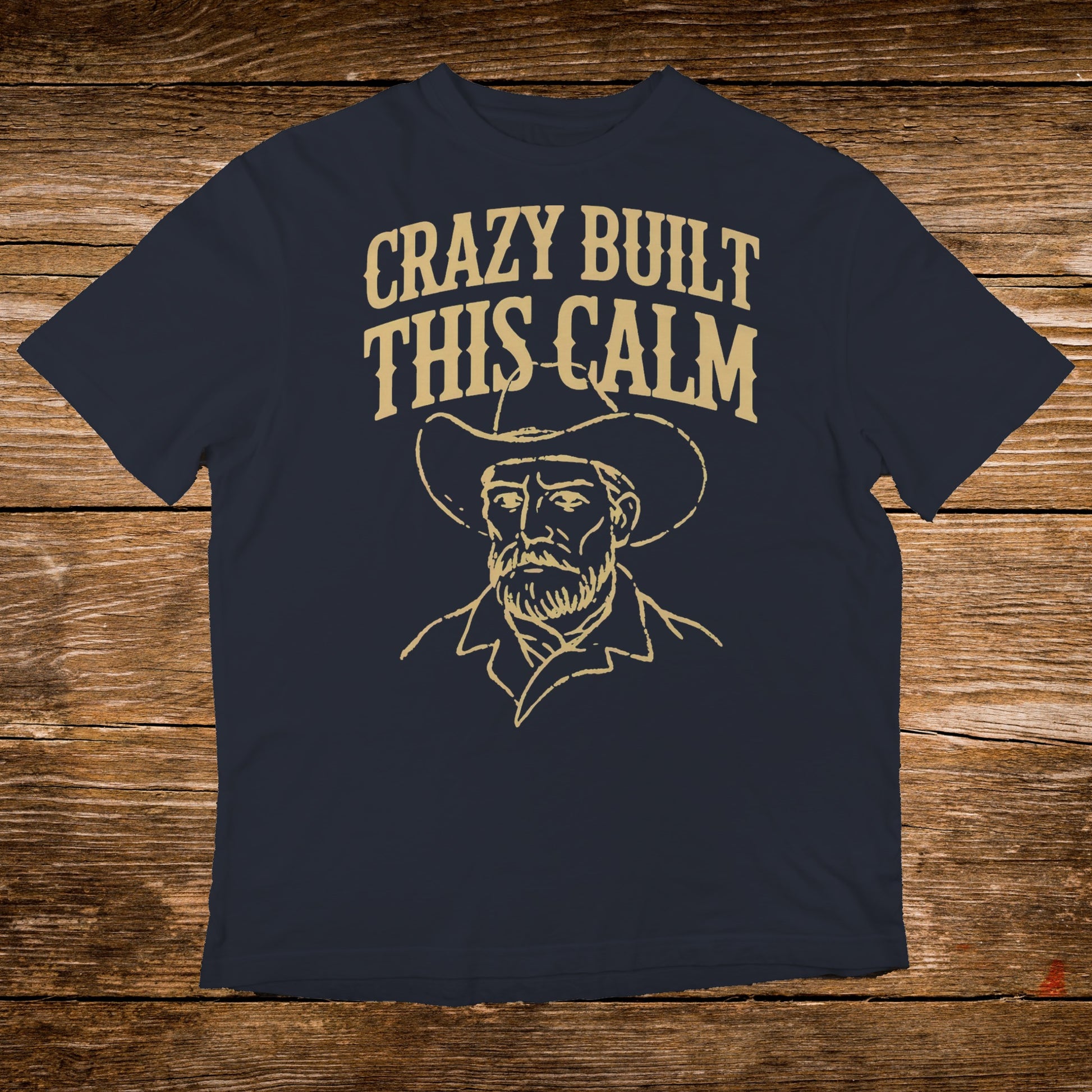Dark t-shirt with a line drawing of a cowboy and "CRAZY BUILT THIS CALM" text.