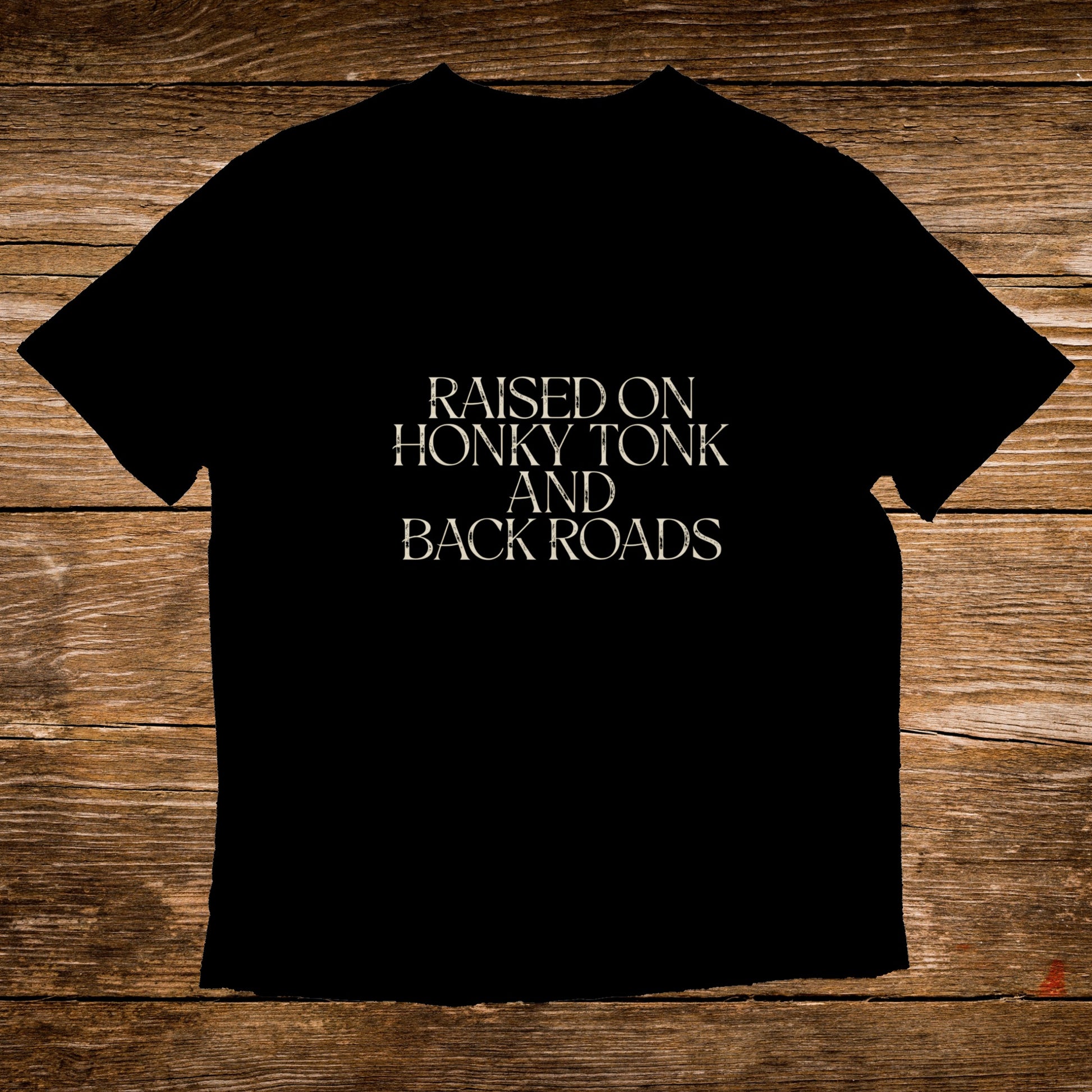 Black t-shirt with text "RAISED ON HONKY TONK AND BACK ROADS".