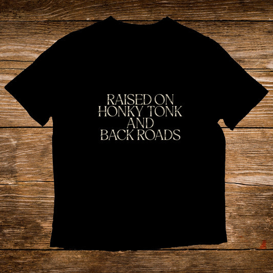 Black t-shirt with text "RAISED ON HONKY TONK AND BACK ROADS".