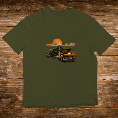 Olive green t-shirt with a vintage truck and sunset graphic on a wooden background.