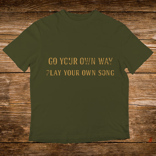 Olive green t-shirt with gold text "GO YOUR OWN WAY PLAY YOUR OWN SONG".