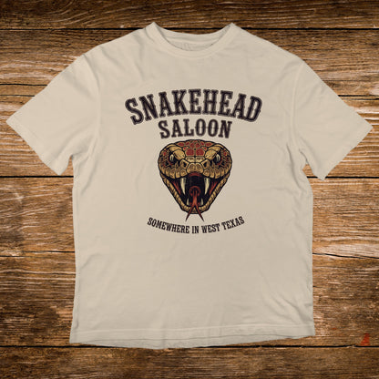 Cream t-shirt with Snakehead Saloon logo featuring a snake's head and "Somewhere in West Texas".
