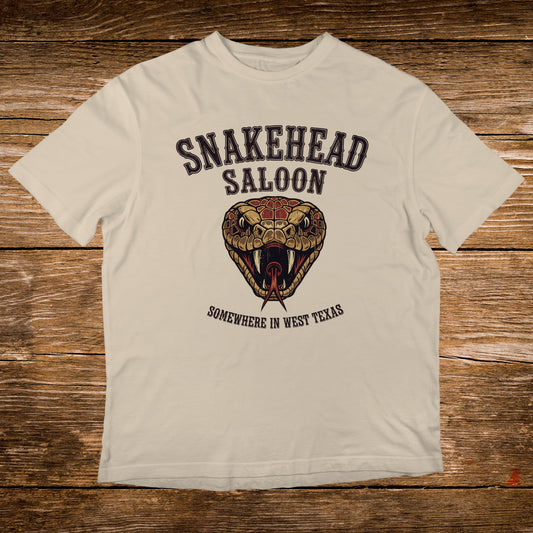 Cream t-shirt with Snakehead Saloon logo featuring a snake's head and "Somewhere in West Texas".