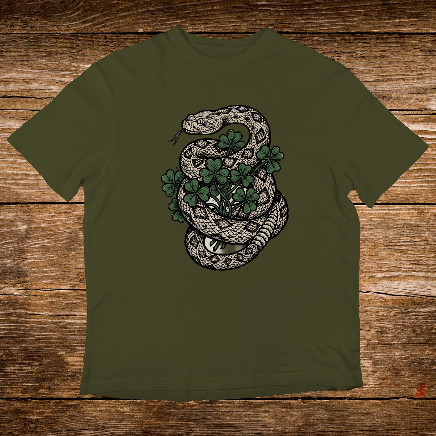 Rattlesnake coiled around green clover on a dark green t-shirt.