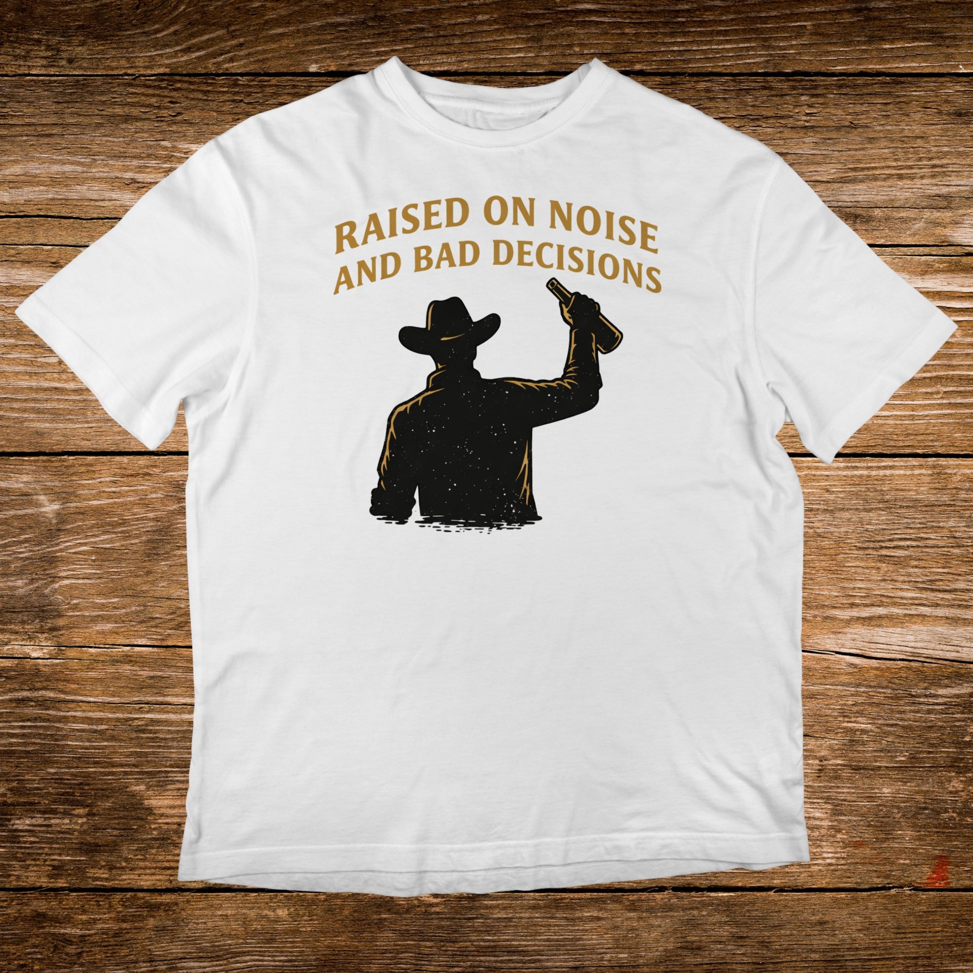 White t-shirt with silhouette of cowboy raising a bottle, text "Raised on noise and bad decisions".