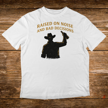 White t-shirt with silhouette of cowboy raising a bottle, text "Raised on noise and bad decisions".
