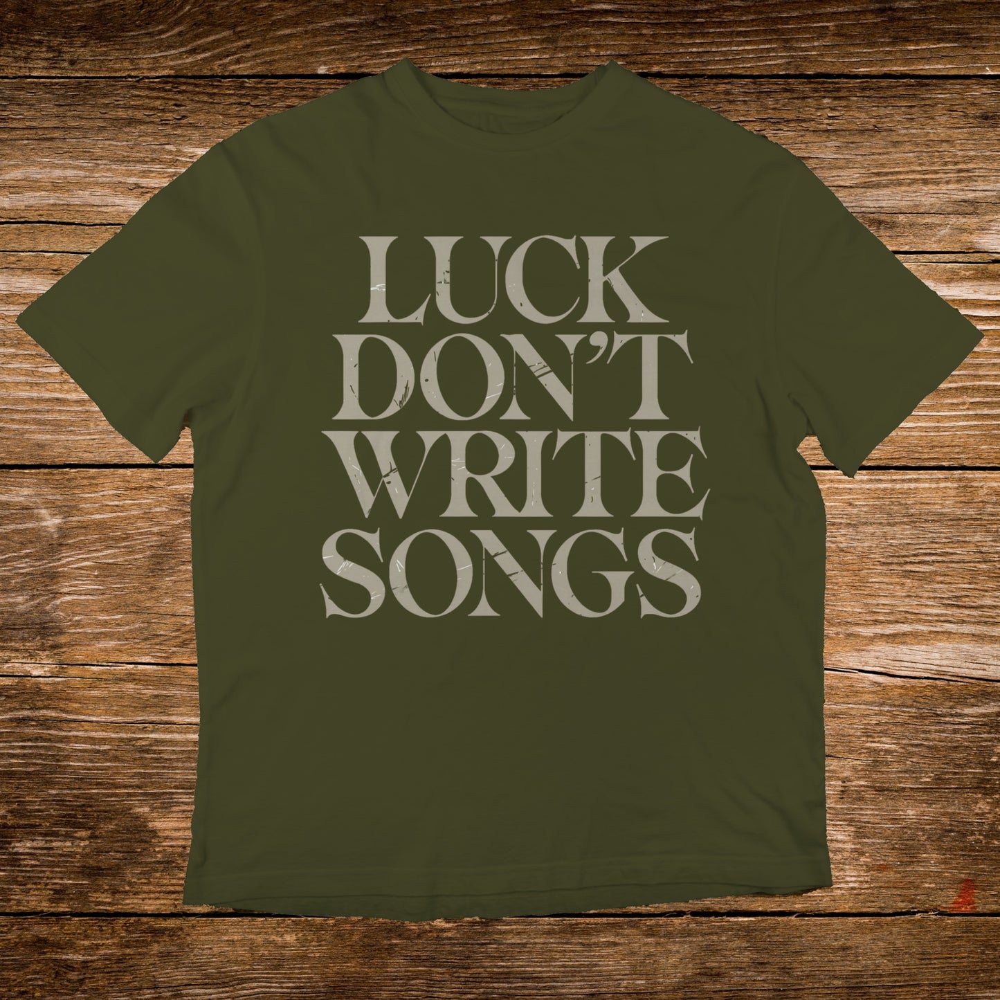 Olive t-shirt with "LUCK DON'T WRITE SONGS" text in gray.