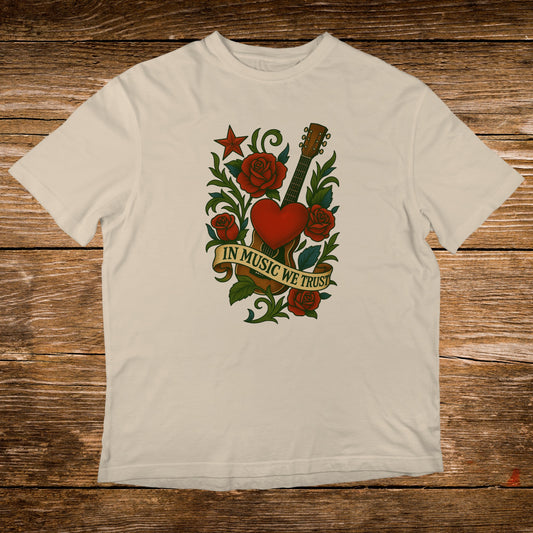 Cream t-shirt with a vintage tattoo design of a guitar, heart, roses, and the text "In Music We Trust".
