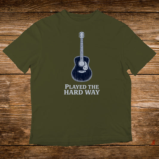 Olive t-shirt with a blue acoustic guitar and text "PLAYED THE HARD WAY".