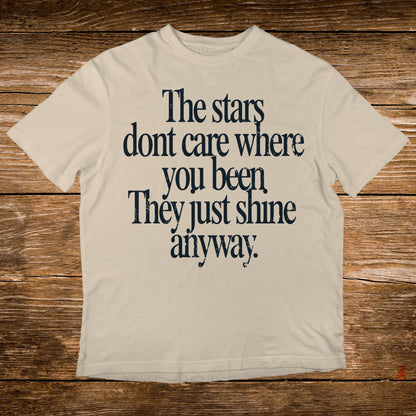 Cream t-shirt with "The stars dont care where you been. They just shine anyway." text.