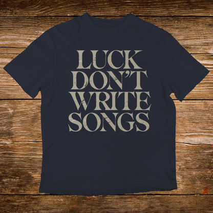 Navy t-shirt with "LUCK DON'T WRITE SONGS" text in distressed beige.