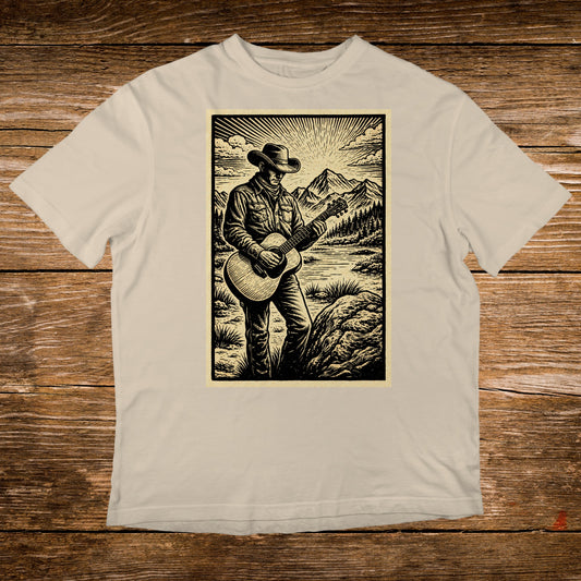Man in cowboy hat playing guitar in mountainous landscape.