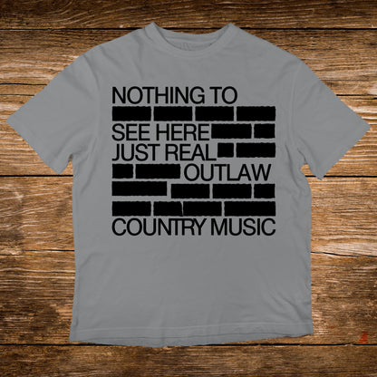 Grey t-shirt with black brick pattern text: "NOTHING TO SEE HERE JUST REAL OUTLAW COUNTRY MUSIC."