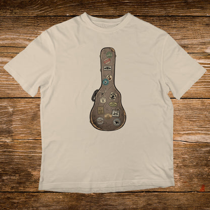 Cream t-shirt with a vintage guitar case design adorned with travel stickers.