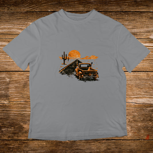 Orange pickup truck with guitar driving towards desert sunset.