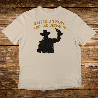 T-shirt with silhouette of cowboy raising bottle, text "RAISED ON NOISE AND BAD DECISIONS".