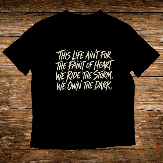 Black t-shirt with white text: "This life ain't for the faint of heart. We ride the storm, we own the dark."