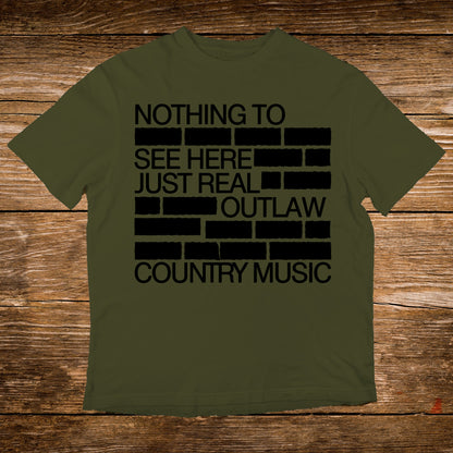 Olive green t-shirt with "NOTHING TO SEE HERE JUST REAL OUTLAW COUNTRY MUSIC" text.