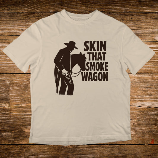 Light tan t-shirt with silhouette of cowboy and horse, text "SKIN THAT SMOKE WAGON".