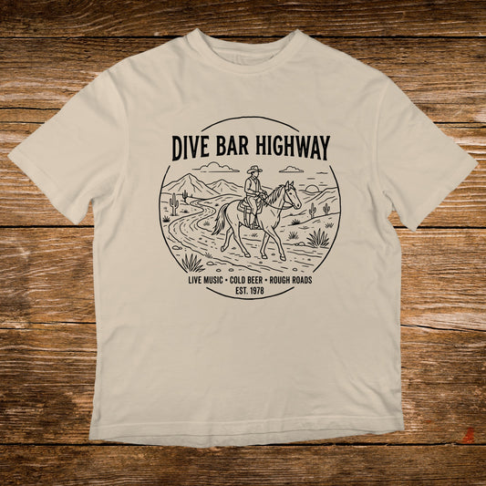 T-shirt with "DIVE BAR HIGHWAY" and horse rider graphic, "LIVE MUSIC COLD BEER ROUGH ROADS EST. 1978".