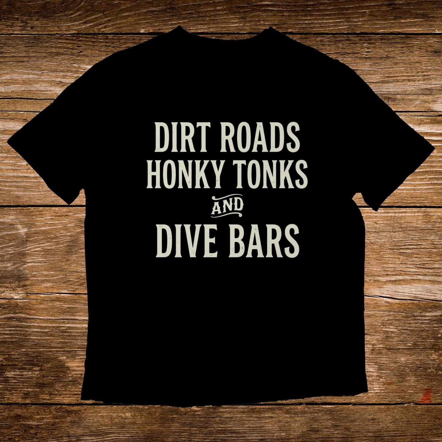 Black t-shirt with white text "Dirt Roads Honky Tonks and Dive Bars".