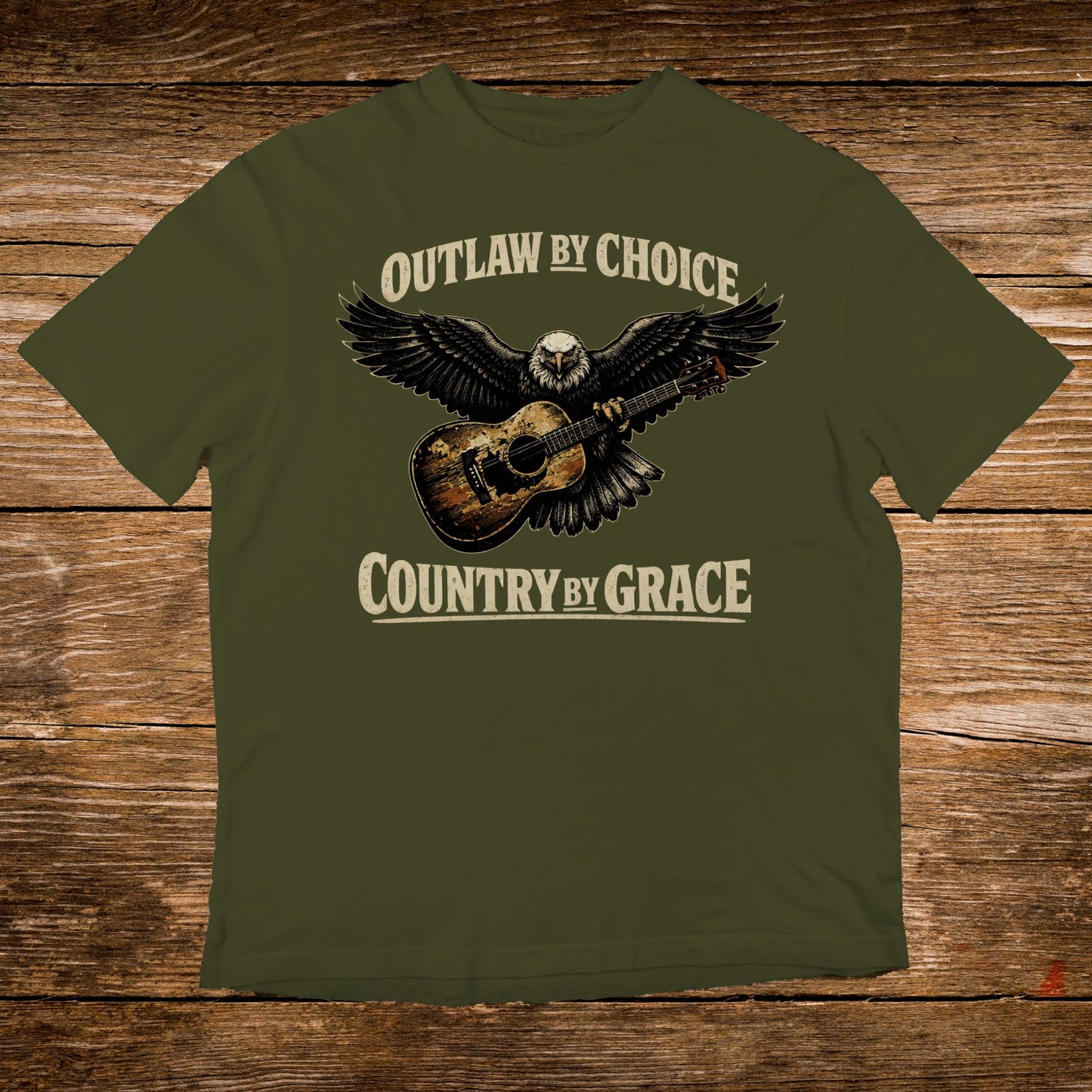 Olive green t-shirt with an eagle and guitar graphic, text reads "Outlaw by Choice, Country by Grace".