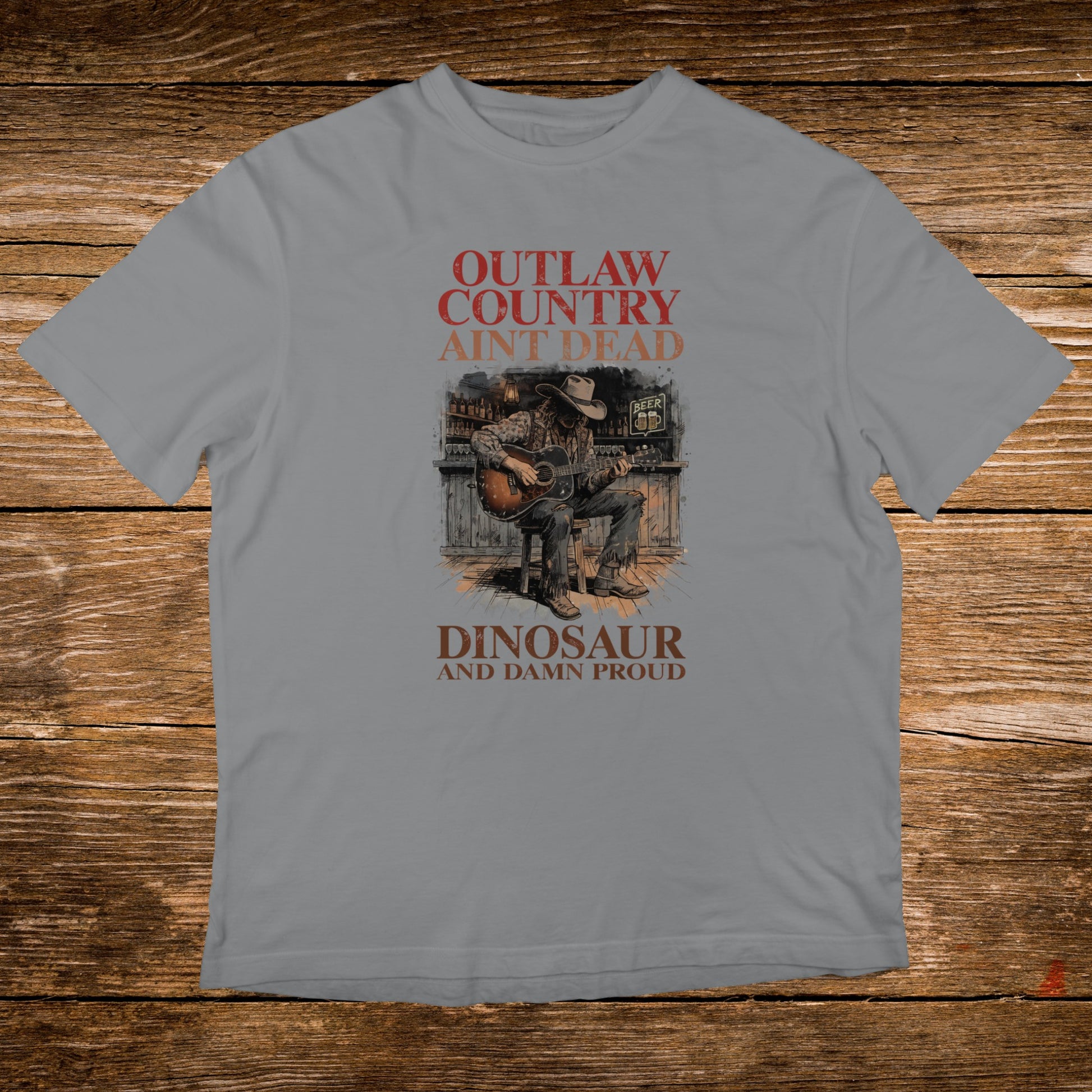 T-shirt with text "OUTLAW COUNTRY AIN'T DEAD" and a cowboy playing guitar.