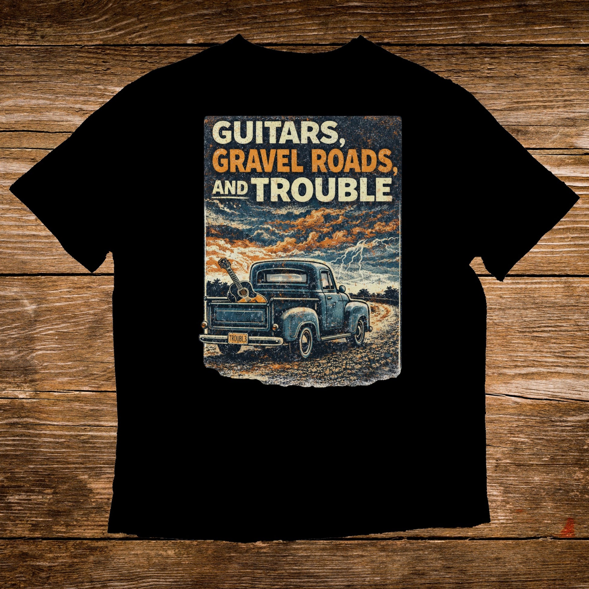 Black t-shirt with distressed graphic of vintage truck, guitar, and text "Guitars, Gravel Roads, and Trouble."