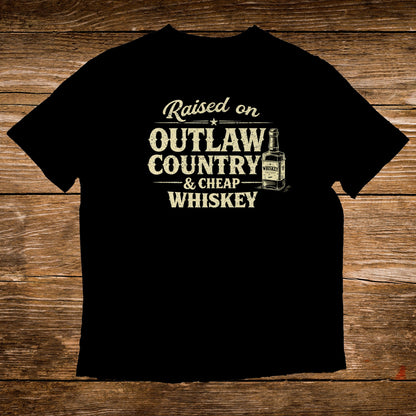 Black t-shirt with "Raised on Outlaw Country & Cheap Whiskey" text and a whiskey bottle graphic.