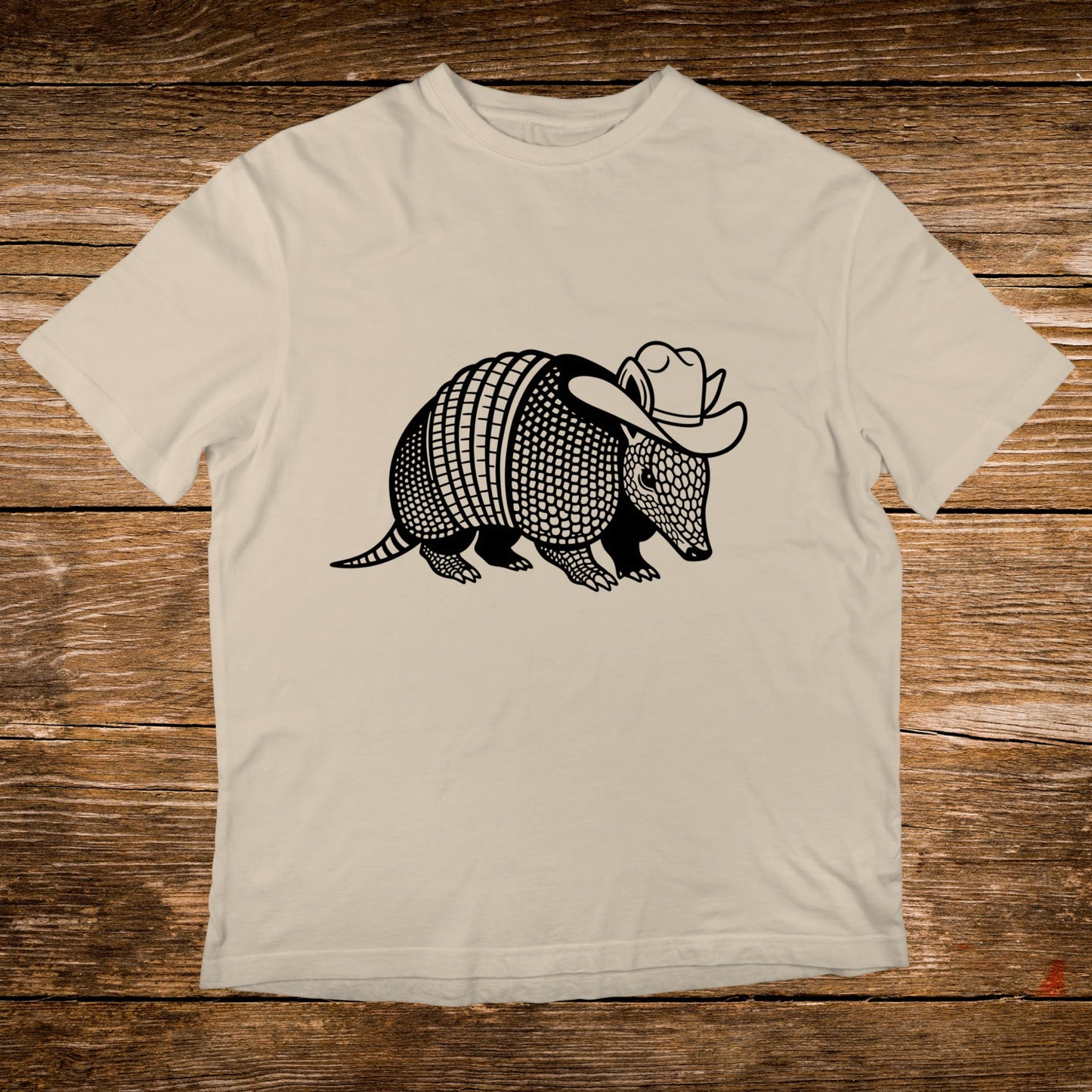 Armadillo wearing a cowboy hat graphic on a cream t-shirt.